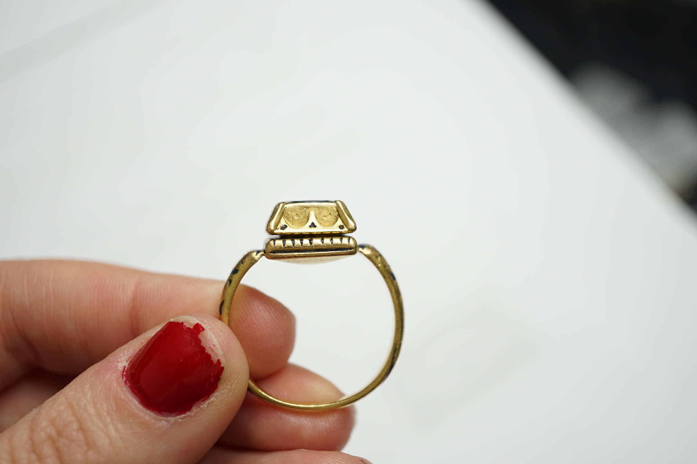 An antique high carat gold, black enamel and collet set cushion cut sapphire set 'poison' ring